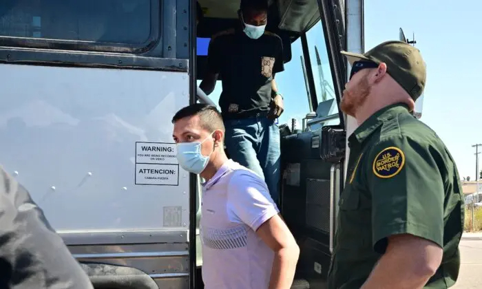 Un agente de la Patrulla Fronteriza estadounidense observa cómo inmigrantes ilegales procedentes de Texas descienden de un autobús en San Diego, California, el 10 de octubre de 2023. (Frederic J. Brown/AFP vía Getty Images)