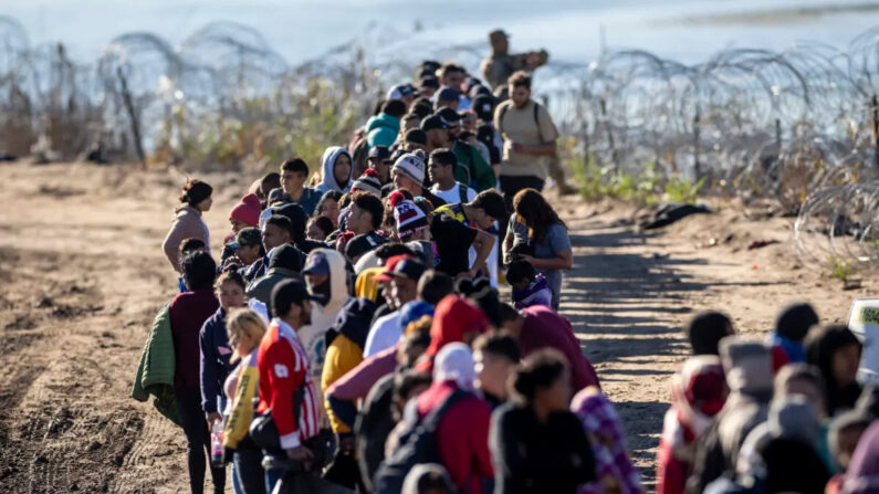 Un grupo de más de 1000 inmigrantes ilegales esperan en fila cerca de un centro de procesamiento de campo de la Patrulla Fronteriza de EE. UU. después de cruzar el Río Grande desde México, en Eagle Pass, Texas, el 18 de diciembre de 2023. (John Moore/Getty Images)
