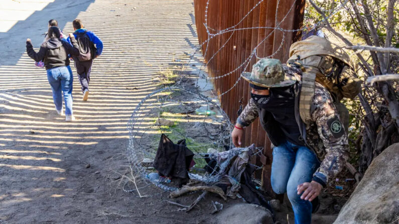 Extranjeros ilegales pasan a través de una brecha en el muro fronterizo de EE. UU. a la espera de ser procesados por agentes de la Patrulla Fronteriza en Jacumba, California, el 7 de diciembre de 2023. (John Fredricks/The Epoch Times)
