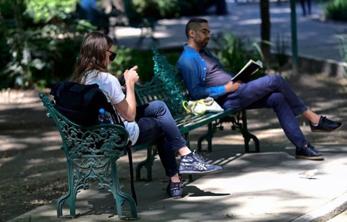 Una joven (izq.) mira su smartphone sentada en un banco de un parque, en Ciudad de México, el 2 de febrero de 2023. (PEDRO PARDO/AFP vía Getty Images)
