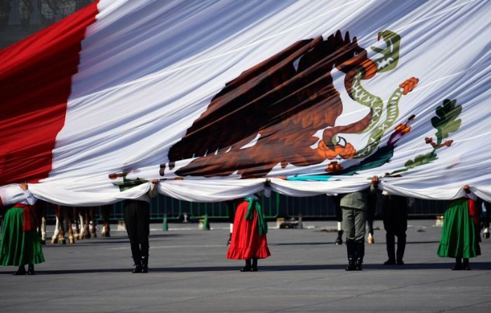 Participantes sostienen una enorme bandera mexicana durante un desfile para conmemorar el 113 aniversario de la Revolución Mexicana, en la Plaza del Zócalo en la Ciudad de México, el 20 de noviembre de 2021. (CLAUDIO CRUZ/AFP vía Getty Images)