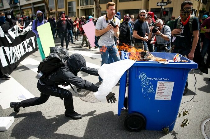 Un extremista Antifa empuja un contenedor de reciclaje en llamas contra partidarios de Trump durante una manifestación por la libertad de expresión en Berkeley, California, el 15 de abril de 2017. (Elijah Nouvelage/Getty Images)