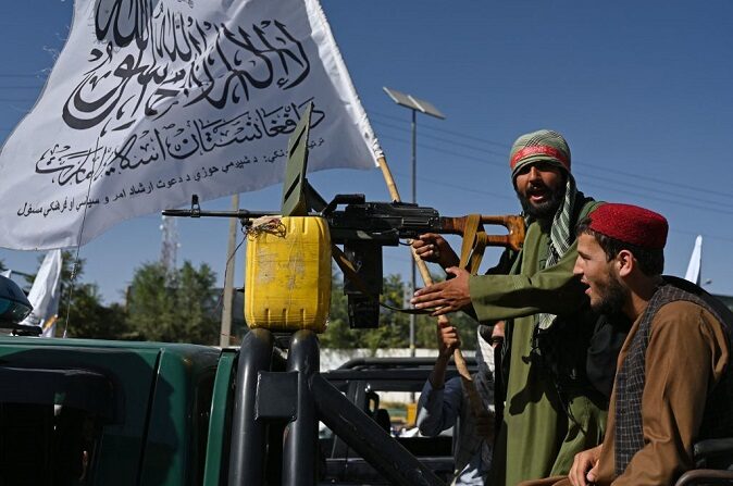 El 15 de agosto de 2023, durante las celebraciones del segundo aniversario de la toma del poder por los talibanes en Kabul, un elemento de seguridad talibán coloca a un lado un bote amarillo que simula contener explosivos durante un desfile cerca de la torre de seguridad de la embajada estadounidense desalojada. (WAKIL KOHSAR/AFP vía Getty Images)