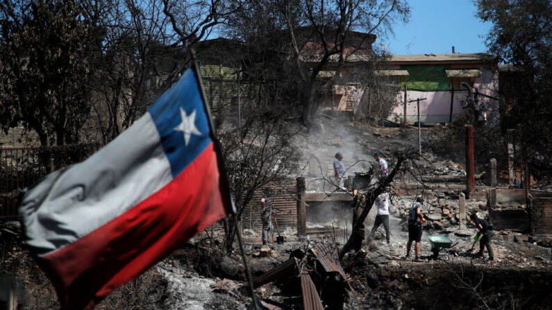Una bandera chilena ondea mientras los vecinos limpian sus tierras y casas quemadas en Villa Independencia, región de Valparaíso, Chile, el 5 de febrero de 2024. (Javier Torres/AFP vía Getty Images)