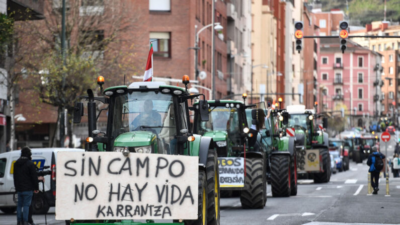 Una pancarta en un tractor reza "Sin campo no hay vida" mientras los agricultores conducen sus vehículos durante una protesta en el centro de la ciudad vasca española de Bilbao, el 9 de febrero de 2024. (Ander Gillenea/AFP vía Getty Images)