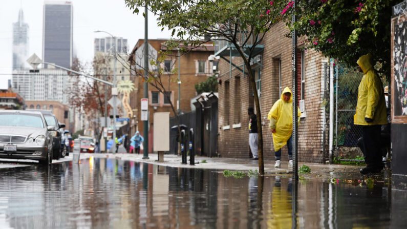 La gente se para en el centro de la ciudad bajo la lluvia mientras una poderosa tormenta fluvial atmosférica de larga duración, la segunda en menos de una semana, continúa impactando el sur de California el 6 de febrero de 2024 en Los Ángeles, California (EE.UU.). (Mario Tama/Getty Images)
