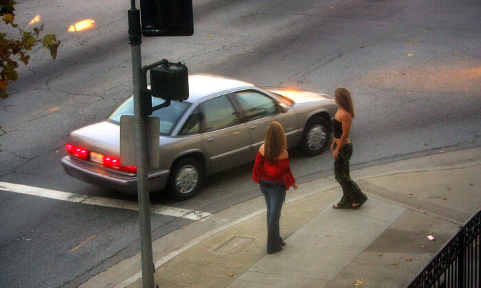 Un automóvil reduce la velocidad ante dos mujeres policías que se hacen pasar por prostitutas en Holt Boulevard, conocido por las trabajadoras sexuales en todo el sur de California como "la pista", durante una importante operación encubierta de prostitución, el 12 de noviembre de 2004, en Pomona, California. (David McNew/Getty Images) 