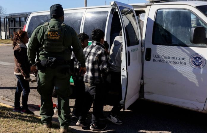 Un agente de la Patrulla Fronteriza guía a los migrantes que cruzaron a Shelby Park a una camioneta de la Patrulla Fronteriza para ser llevados a un centro de procesamiento el 4 de febrero de 2024 en Eagle Pass, Texas. (Michael Gonzalez/Getty Images)