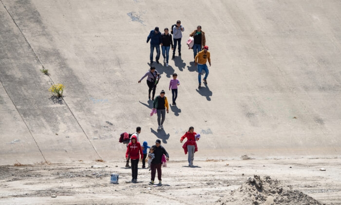 Migrantes cruzan el cauce del río Tijuana en dirección al puerto de entrada a Estados Unidos de San Diego el 11 de mayo de 2023. (John Fredricks/The Epoch Times)
