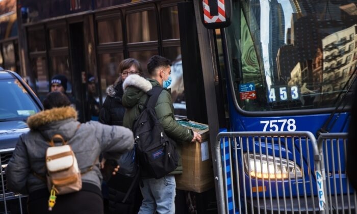 Inmigrantes ilegales llevan sus pertenencias a un autobús tras aceptar ser realojados después de ser desalojados del Hotel Watson en Nueva York el 30 de enero de 2023. (Michael M. Santiago/Getty Images)