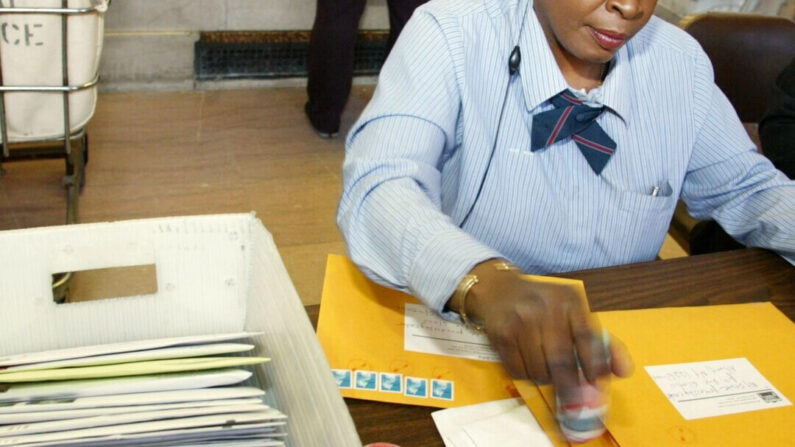 En una foto de archivo, se ve a un trabajador postal poniendo sellos en sobres destinados al IRS. (Monika Graff/Getty Images)