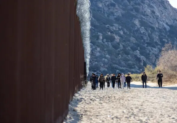 Inmigrantes ilegales que pasaron por una brecha en el muro fronterizo de Estados Unidos esperan ser procesados por agentes de la Patrulla Fronteriza, en Jacumba, California, el 7 de diciembre de 2023. (John Fredricks/The Epoch Times)