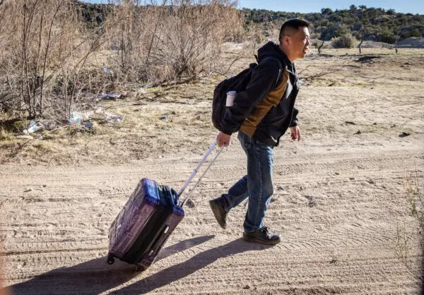 Un inmigrante ilegal chino avanza hacia una apertura en el muro fronterizo de Estados Unidos en Jacumba, California, el 6 de diciembre de 2023. (John Fredricks/The Epoch Times)
