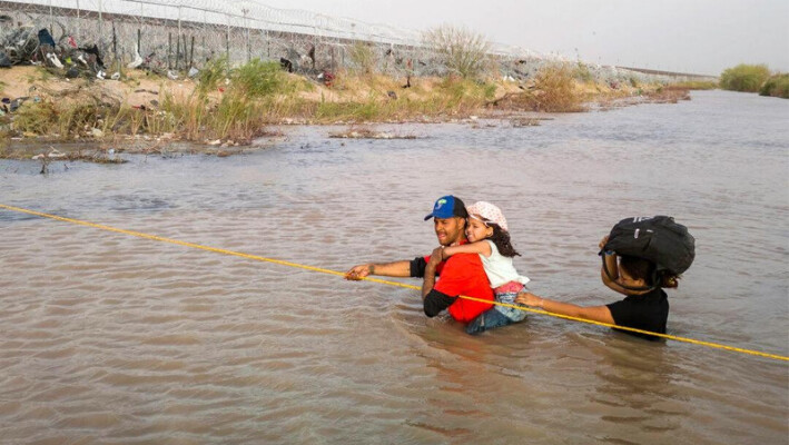 Inmigrantes ilegales vadean el río Grande mientras cruzan la frontera entre Estados Unidos y México para pedir asilo, en El Paso, Texas, el 13 de marzo de 2024. (John Moore/Getty Images)