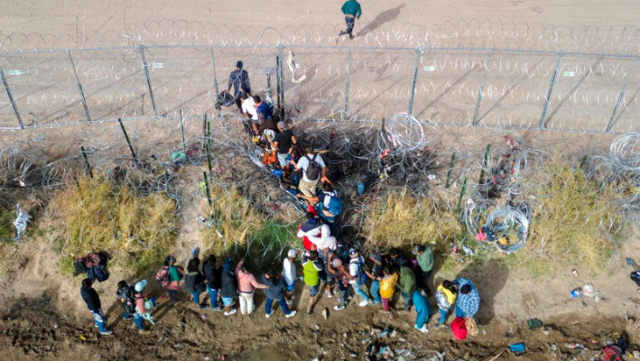 Inmigrantes ilegales atraviesan espirales de alambre de espino mientras cruzan la frontera entre Estados Unidos y México en El Paso, Texas, el 13 de marzo de 2024. (John Moore/Getty Images)