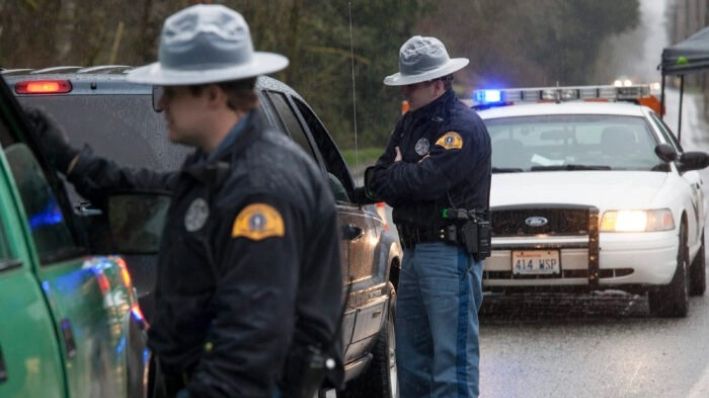 Los agentes de la Patrulla Estatal de Washington detienen vehículos en un control de carretera en la autopista 530 de Washington, cerca de un enorme deslizamiento de tierra en Darrington, Washington, el 28 de marzo de 2014. (David Ryder/Getty Images)