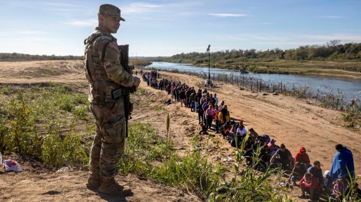 Un soldado de la Guardia Nacional de Texas vigila a un grupo de más de 1000 migrantes que cruzaron el Río Grande desde México en Eagle Pass, Texas, el 18 de diciembre de 2023. (John Moore/Getty Images)