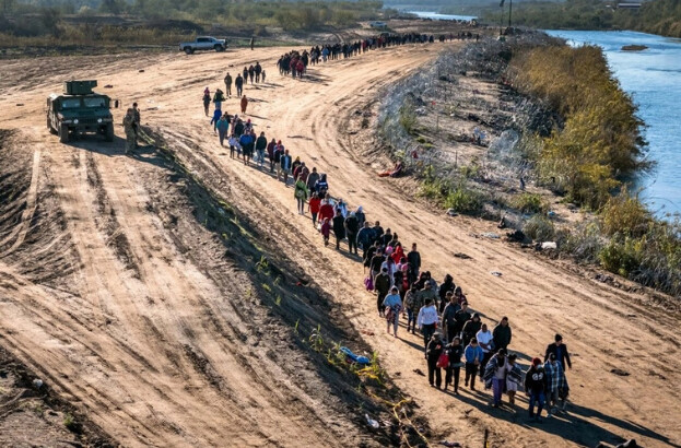 En esta vista aérea, Un grupo de más de 1000 inmigrantes camina hacia un centro de procesamiento de campo de la Patrulla Fronteriza de EE.UU. después de cruzar el Río Grande desde México en Eagle Pass, Texas, el 18 de diciembre de 2023. (John Moore/Getty Images)
