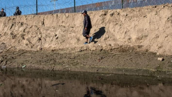 Un hombre que viaja con una caravana de migrantes centroamericanos -en su mayoría de Honduras- con la esperanza de llegar a Estados Unidos, camina cerca de una barricada colocada por la Patrulla Fronteriza de Estados Unidos a lo largo del río Tijuana, cerca del cruce fronterizo de El Chaparral en Tijuana, México, el 25 de noviembre de 2018. (Guillermo Arias/AFP vía Getty Images)