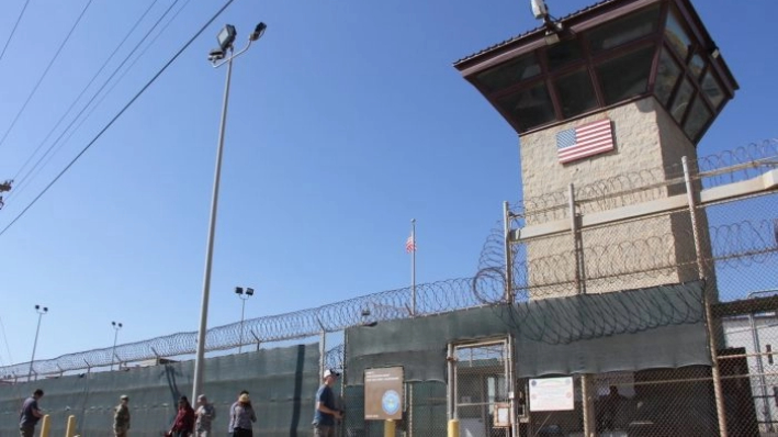 Un grupo de personas pasa junto a una torre de vigilancia frente al vallado del Campo 5 de la prisión militar estadounidense de Guantánamo, Cuba, el 26 de enero de 2017. (Thomas Watkins/AFP/Getty Images