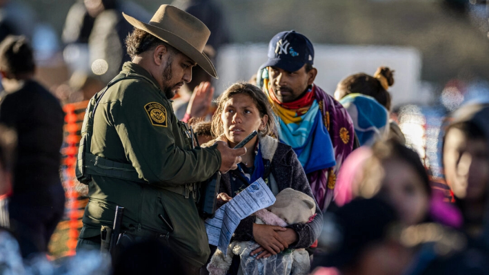 Un agente de la Patrulla Fronteriza de Estados Unidos habla con inmigrantes ilegales en un centro de tránsito cerca de la frontera entre Estados Unidos y México en Eagle Pass, Texas, el 19 de diciembre de 2023. (John Moore/Getty Images)