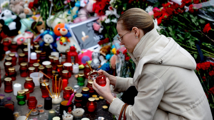 Una mujer enciende una vela en un monumento a las víctimas de un ataque a tiros en la sala de conciertos Crocus City Hall, cerca de Moscú, el 24 de marzo de 2024. (Maxim Shemetov/Reuters)