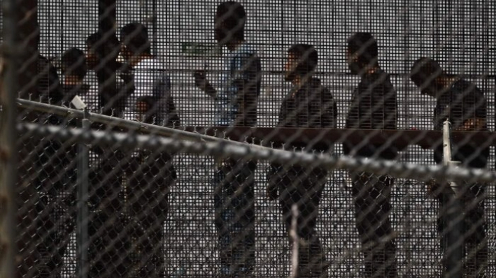 Inmigrantes ilegales esperan a lo largo del muro fronterizo para subir a un autobús después de entregarse a los agentes de la Patrulla Fronteriza de Aduanas y Protección Fronteriza de EE.UU. (CBP) en la frontera entre EE.UU. y México en El Paso, Texas, el 12 de mayo de 2023. (Patrick T. Fallon/AFP vía Getty Images)