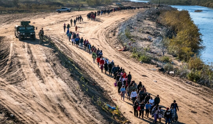 Un grupo de más de 1000 inmigrantes ilegales camina hacia un centro de procesamiento de campo de la Patrulla Fronteriza de EE. UU. después de cruzar el Río Grande desde México en Eagle Pass, Texas, el 18 de diciembre de 2023. (John Moore/Getty Images)
