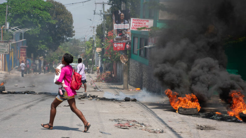 Una mujer con un niño en brazos huye de la zona tras escucharse disparos en Puerto Príncipe, Haití, el 20 de marzo de 2024. (Clarens Siffroy/AFP vía Getty Images)