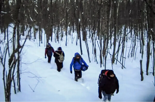 Inmigrantes ilegales caminando sobre la nieve 