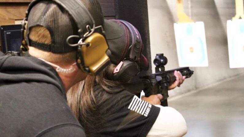Una asistente al Día Nacional de la Mujer dispara un rifle semiautomático en el campo de tiro cubierto Texas Gun Experience el 9 de marzo de 2024 mientras un oficial/instructor observa. (Michael Clements/The Epoch Times)