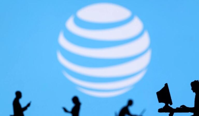Pequeñas figuras con ordenadores portátiles y teléfonos inteligentes se ven delante del logotipo de AT&T, el 5 de diciembre de 2021. (Dado Ruvic/Reuters, Ilustración)