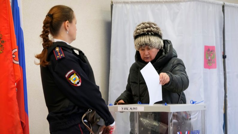 Una mujer vota mientras un oficial de policía vigila un colegio electoral durante las elecciones presidenciales en San Petersburgo, Rusia, el domingo 17 de marzo de 2024. (AP/Dmitri Lovetsky)