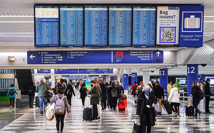 Los viajeros recogen su equipaje en el área de recogida de equipaje después de llegar al Aeropuerto Internacional O'Hare de Chicago, el 11 de marzo de 2022. (Scott Olson/Getty Images)
