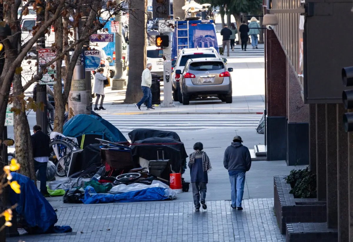 La gente pasa junto a personas sin hogar en Los Ángeles. California, el 11 de enero de 2024. (John Fredricks/The Epoch Times)