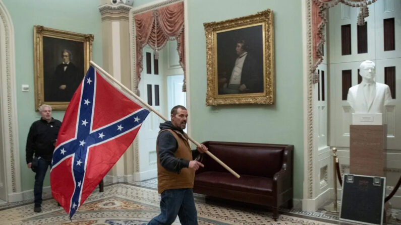 Kevin Seefried sostiene una bandera confederada frente a la Cámara del Senado durante una protesta tras irrumpir en el Capitolio de EE. UU., en Washington, el 6 de enero de 2021. (Saul Loeb/AFP/Getty Images)
