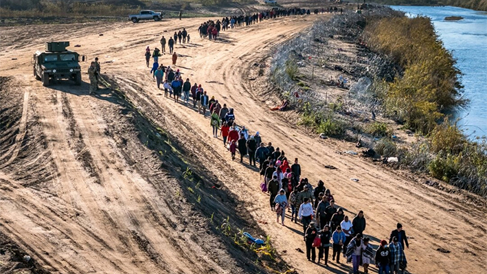 Un grupo de más de 1000 inmigrantes ilegales camina hacia un centro de procesamiento de campo de la Patrulla Fronteriza estadounidense tras cruzar el Río Grande desde México en Eagle Pass, Texas, el 18 de diciembre de 2023. (John Moore/Getty Images)
