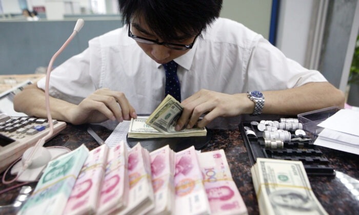 Un empleado cuenta pilas de yuanes chinos y dólares estadounidenses en un banco de Shanghai, China, el 22 de julio de 2005. (China Photos/Getty Images)