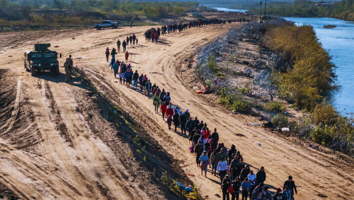 En esta vista aérea, un grupo de más de 1.000 inmigrantes camina hacia un centro de procesamiento de campo de la Patrulla Fronteriza de EE.UU. después de cruzar el Río Grande desde México en Eagle Pass, Texas, el 18 de diciembre de 2023. (John Moore/Getty Images)