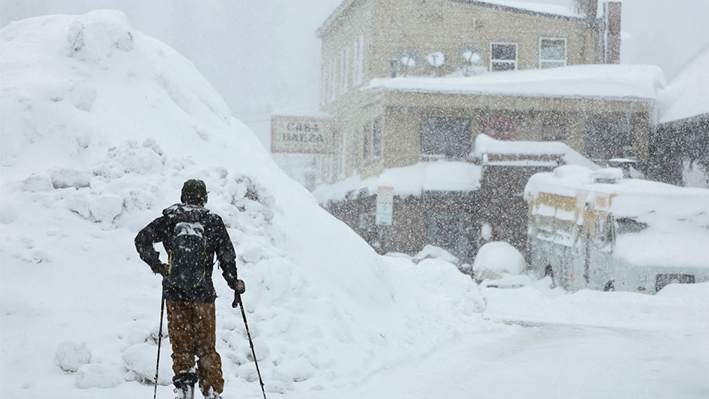Una persona utiliza los esquís en el centro de la ciudad mientras la nieve sigue cayendo durante una potente tormenta invernal de varios días en las montañas de Sierra Nevada, en Truckee, California, el 3 de marzo de 2024. (Mario Tama/Getty Images)
