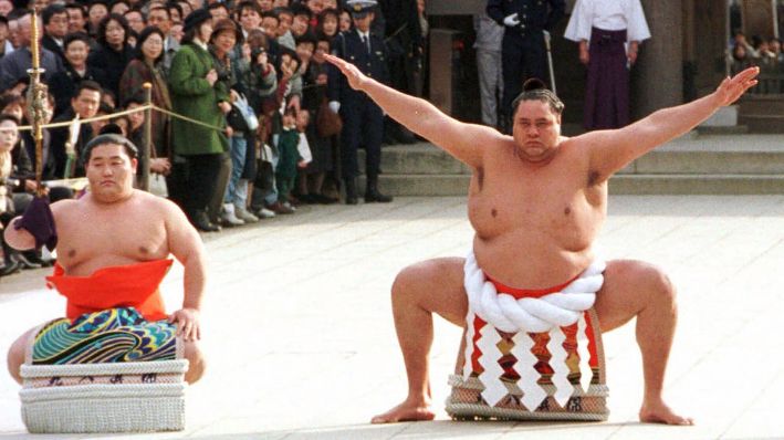 Acompañado por un portador de espada, el gran campeón Akebono realiza el ritual de entrada al ring durante la dedicación anual de Año Nuevo en el Santuario Meiji en Tokio, el 8 de enero de 1997. (AP Photo/Koji Sasahara, Archivo)