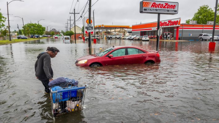 La gente carga sus pertenencias por una calle Broad inundada en Nueva Orleans, durante una fuerte tormenta, el miércoles 10 de abril de 2024. (Chris Granger/The Times-Picayune/The New Orleans Advocate vía AP)
