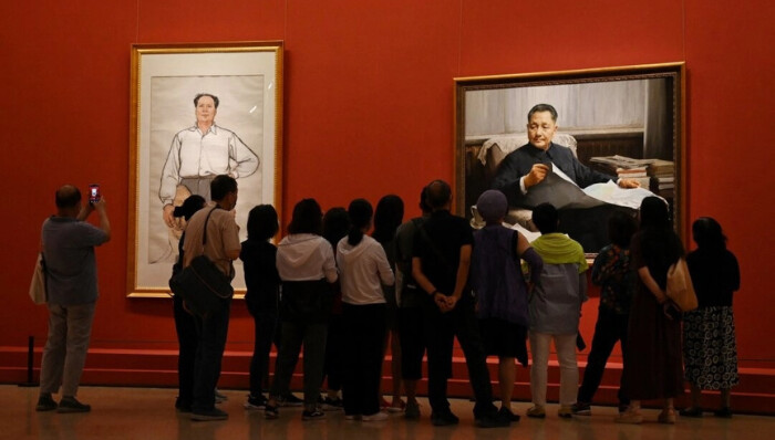 Visitantes observan unas pinturas de los difuntos líderes comunistas Mao Zedong (izq.) y Deng Xiaoping en una exposición de arte que celebra el centenario de la fundación del Partido Comunista en Pekín, el 24 de junio de 2021. (Greg Baker/AFP vía Getty Images)