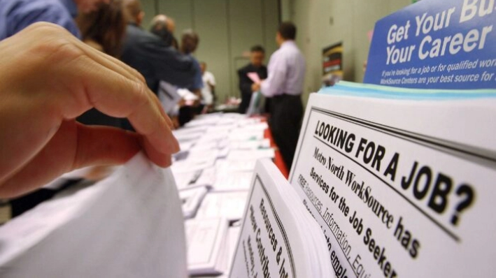 Buscadores de empleo examinan folletos de ofertas de trabajo en una exposición de WorkSource. (David McNew/Getty Images)