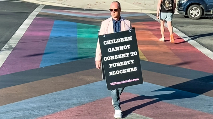 El activista Chris Elton lleva un cartel en el que se lee "Los niños no pueden consentir los bloqueadores de la pubertad" por West Hollywood, California, en 2022. (Cortesía de Billboard Chris)