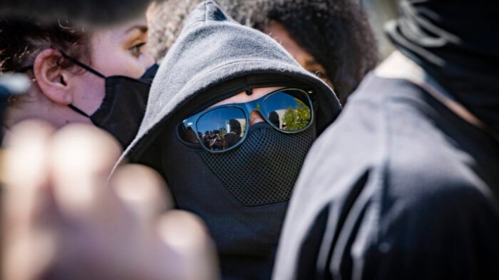 Hombres y mujeres vestidos de negro asistieron a una protesta en Los Ángeles, California, el 20 de octubre de 2021. (John Fredricks/The Epoch Times)