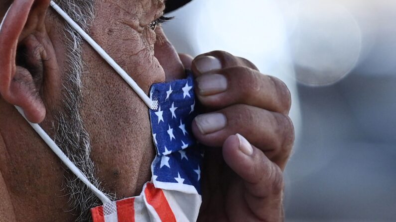 Foto de archivo hombre ajusta su mascarilla facial con la bandera estadounidense. (Robyn Beck/AFP via Getty Images)
