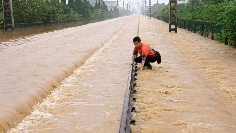 Un empleado ferroviario comprueba una vía férrea inundada tras las fuertes lluvias en Shangrao, en la provincia central china de Jiangxi, el 21 de junio de 2022. (STR/AFP vía Getty Images)