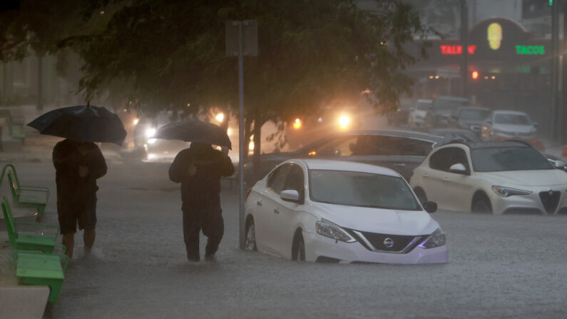 Fotografía de archivo peatones caminan por una calle inundada debido a un aguacero causado por una tormenta tropical que atraviesa la zona el 4 de junio de 2022 en Miami, Florida. (Joe Raedle/Getty Images)