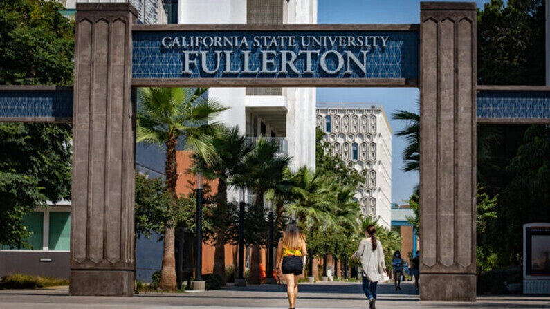 Estudiantes caminan debajo de la entrada del campus de Fullerton de la Universidad Estatal de California, en Fullerton, California, el 28 de agosto de 2020. (John Fredricks/The Epoch Times)

